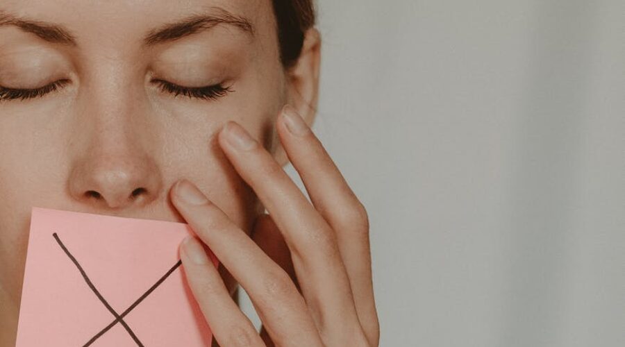 woman with cross symbol on mouth unable to speak