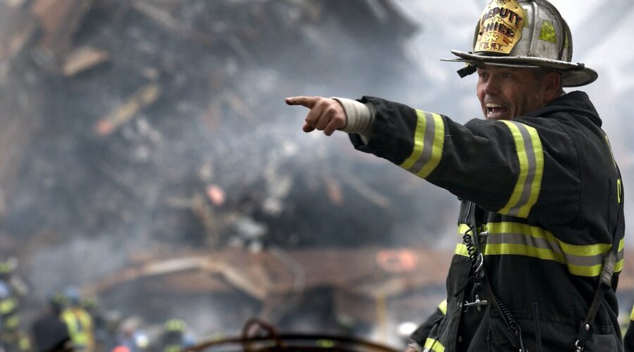 fire fighter wearing black and yellow uniform pointing for something