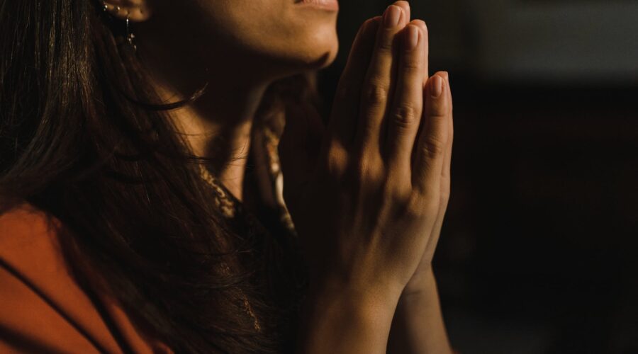 a person in orange shirt with hands together